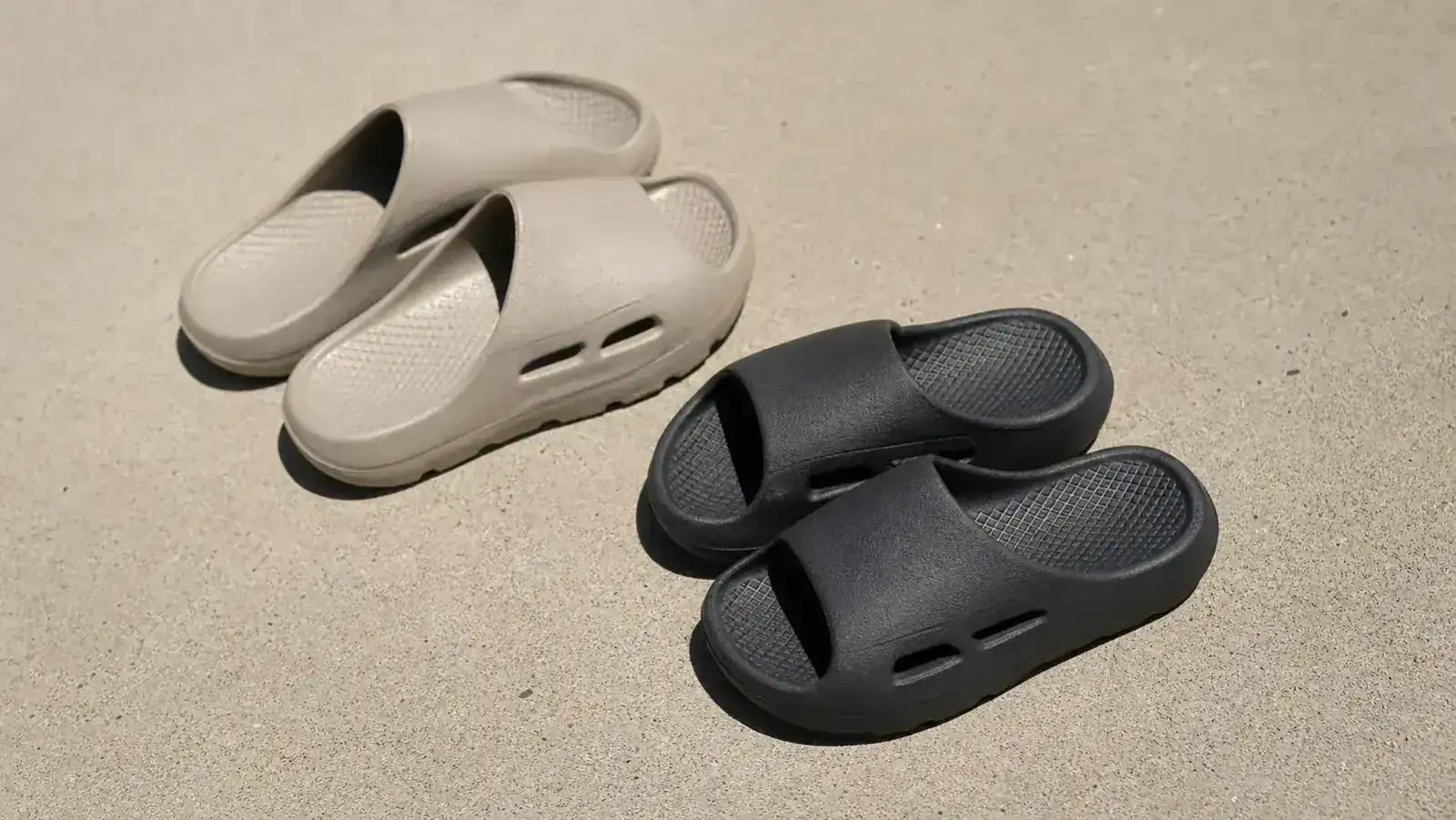 Two pairs of recovery slides side by side on a gym locker room bench, one black and one white, after a training session