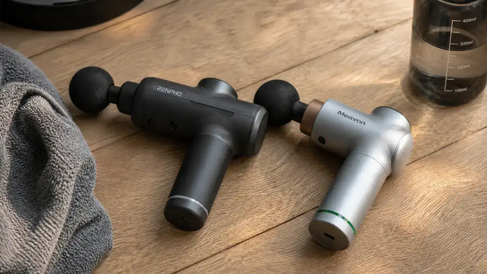 Theragun Relief massage gun resting on a gym bag beside a foam roller and water bottle