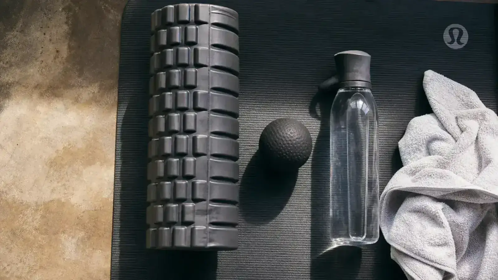 TriggerPoint GRID 2.0 foam roller on a gym floor next to a lacrosse ball, side by side comparison